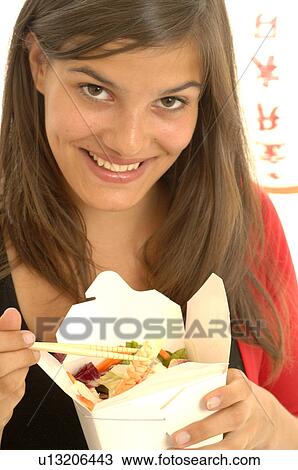 Stock Image - Woman is eating Asian food with chopsticks. Fotosearch