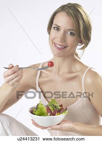 Stock Image - Woman is eating salad. Fotosearch