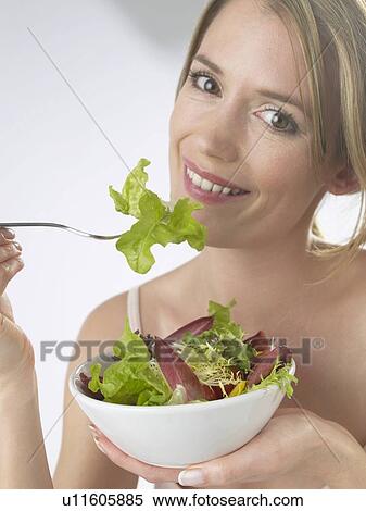 Stock Photography - Woman is eating salad. Fotosearch
