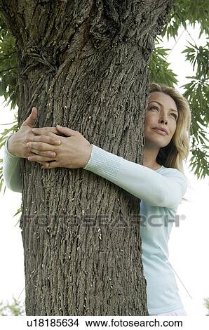 Woman is embracing a tree in a meadow View Large Photo Image Picture - Woman is embracing a tree in a meadow. Fotosearch