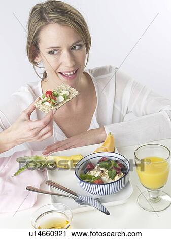 Stock Image - Woman is having breakfast with crispbread and cereals. Fotosearch