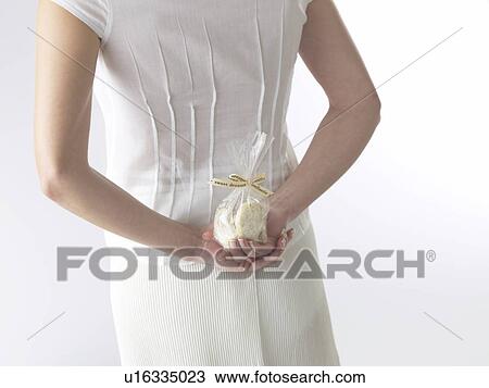 Stock Image - Woman is hiding biscuits behind her back. Fotosearch