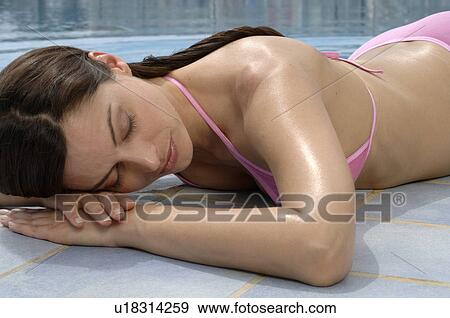 Stock Photo - Woman is lying at the swimming pool - eyes closed. Fotosearch