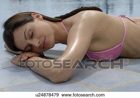 Stock Photo - Woman is lying at the swimming pool - eyes closed. Fotosearch