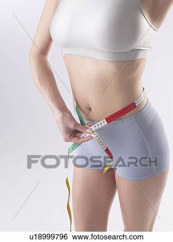 Stock Photograph - Woman is measuring her waist. Fotosearch