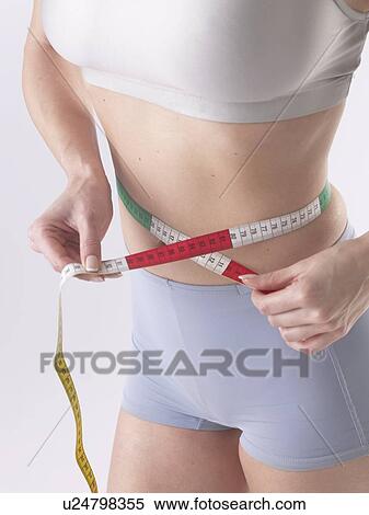 Stock Photography - Woman is measuring her waist. Fotosearch