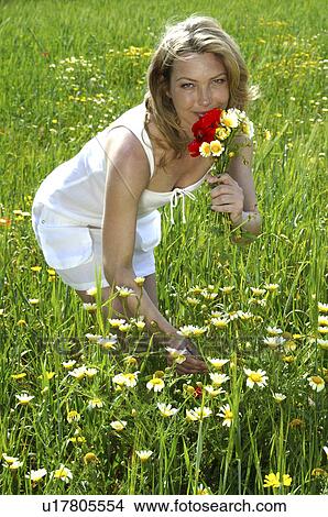 Picture - Woman is picking summer flowers in the meadow. Fotosearch