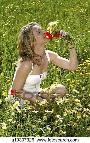 Woman is smelling summer flowers in the meadow View Large Photo Image Stock Photograph - Woman is smelling summer flowers in the meadow. Fotosearch