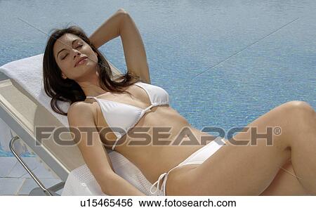 Stock Photograph - Woman is sunbathing at the swimming pool. Fotosearch