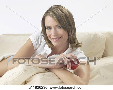 Woman lounging on a sofa View Large Photo Image Stock Photograph - Woman lounging on a sofa. Fotosearch