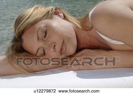 Stock Image - Woman lying on the edge of the swimming pool. Fotosearch