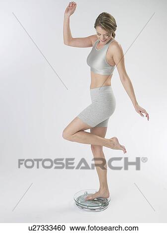 Stock Image - Woman on a bathroom scale. Fotosearch
