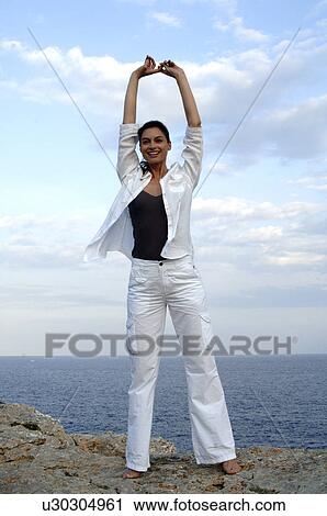 Stock Image - Woman on a rock at the sea. Fotosearch