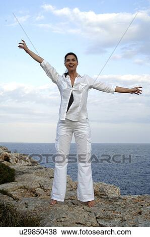Stock Photo - Woman on a rock at the sea. Fotosearch