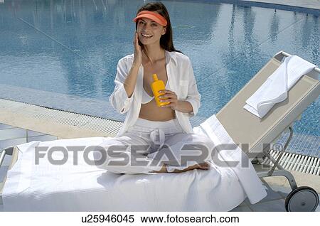 Stock Photography - Woman on a sunlounger is applying sunlotion. Fotosearch
