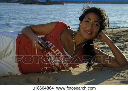 Picture - Woman on the beach listening to music. Fotosearch
