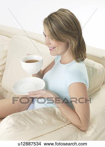 Woman on the sofa drinking a cup of tea View Large Photo Image Picture - Woman on the sofa drinking a cup of tea. Fotosearch