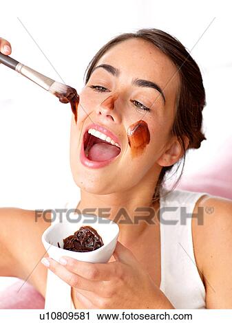 Stock Image - Woman putting on a chocolate face pack. Fotosearch