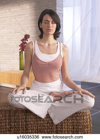 Woman sitting cross-legged doing yoga exercise View Large Photo Image Stock Photograph - Woman sitting cross-legged doing yoga exercise. Fotosearch
