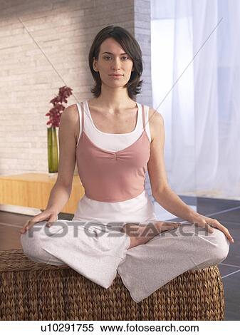 Stock Photography - Woman sitting cross-legged doing yoga exercise. Fotosearch