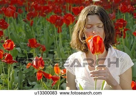Stock Image - Woman smelling at red tulip. Fotosearch