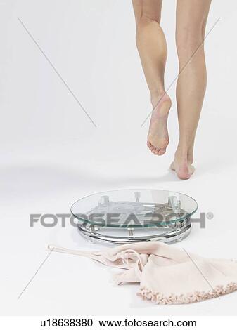 Stock Image - Woman stepping off a bathroom scale. Fotosearch