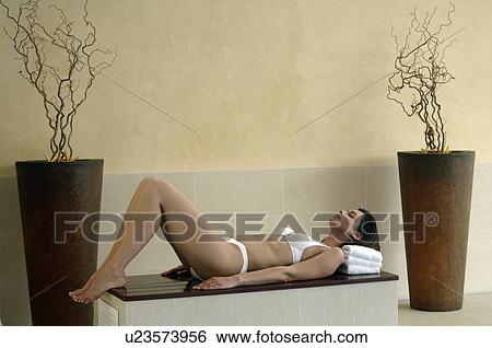Woman wearing bikini is lying on a bench View Large Photo Image Stock Photograph - Woman wearing bikini is lying on a bench. Fotosearch