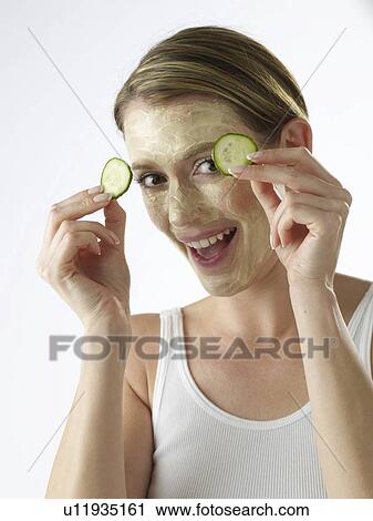 Stock Image - Woman with a cucumber mask. Fotosearch