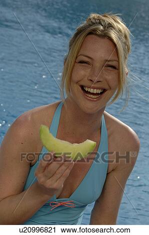 Stock Image - Woman with a piece of honeydew melon. Fotosearch