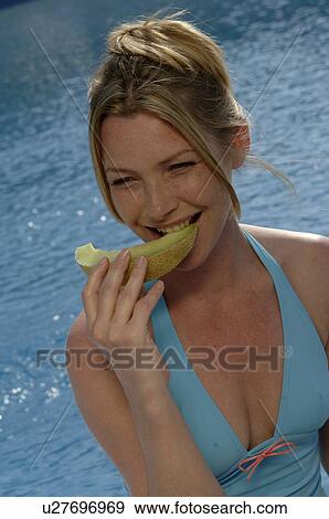 Stock Photo - Woman with a piece of honeydew melon. Fotosearch
