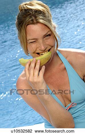 Stock Image - Woman with a piece of sweet melon. Fotosearch