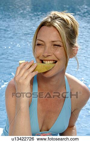 Stock Photograph - Woman with a piece of sweet melon. Fotosearch