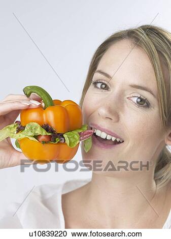 Stock Image - Woman with an orange pepper burger. Fotosearch