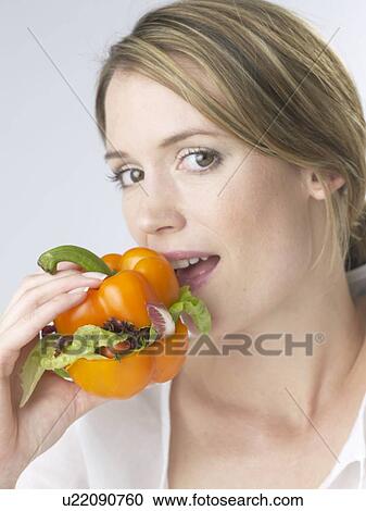 Stock Image - Woman with an orange pepper burger. Fotosearch
