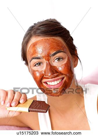 Stock Image - Woman with face pack and chocolate bar. Fotosearch