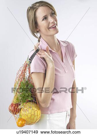 Stock Photo - Woman with fruit and vegetables in a string bag. Fotosearch