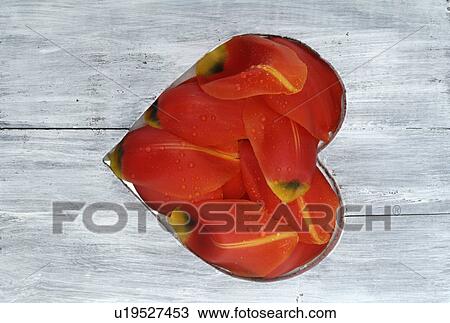 Stock Image - Wooden plank with heart of parrot tulip blossoms. Fotosearch