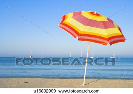 Stock Photo - Yellow and red sunshade on the beach. Fotosearch