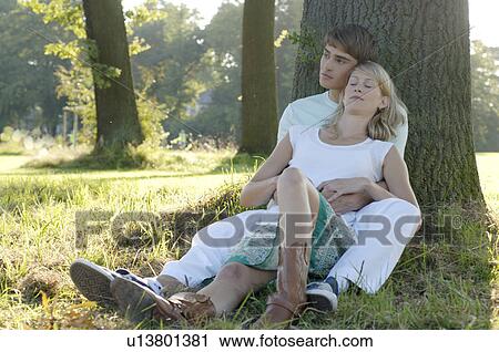 Young couple sitting underneath trea View Large Photo Image Stock Image - Young couple sitting underneath trea. Fotosearch