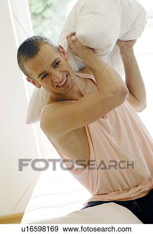 Stock Photo - Young man in a pillow fight. Fotosearch