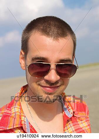 Young man on the beach with sunglasses View Large Photo Image Picture - Young man on the beach with sunglasses. Fotosearch