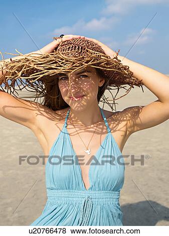 Stock Photo - Young woman in a summerdress and with hat. Fotosearch