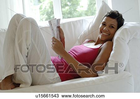 Young woman reading a magazine View Large Photo Image Stock Image - Young woman reading a magazine. Fotosearch
