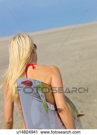 Stock Image - Young woman with a surfboard. Fotosearch