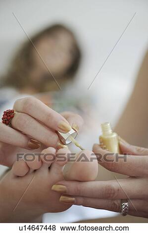 Stock Photo - A girl painting her sister's toenails. Fotosearch