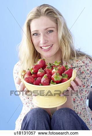 Stock Photo - Blonde woman holding a bowl with strawberries. Fotosearch