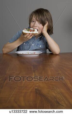Stock Image - Boy eating open-faced sandwich. Fotosearch