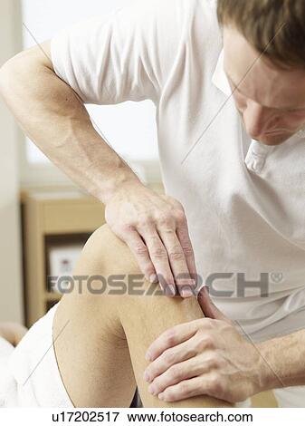 Stock Photo - Chiropractor medicates a woman's knee. Fotosearch
