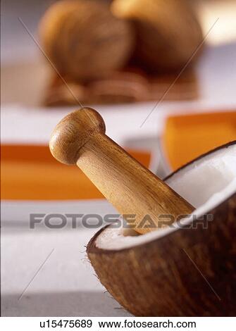 Stock Photo - Coconut half and wooden pestle. Fotosearch
