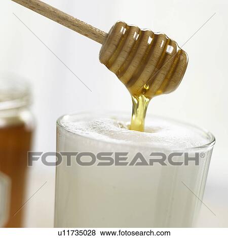 Filling honey into frothy milk View Large Photo Image Stock Photo - Filling honey into frothy milk. Fotosearch